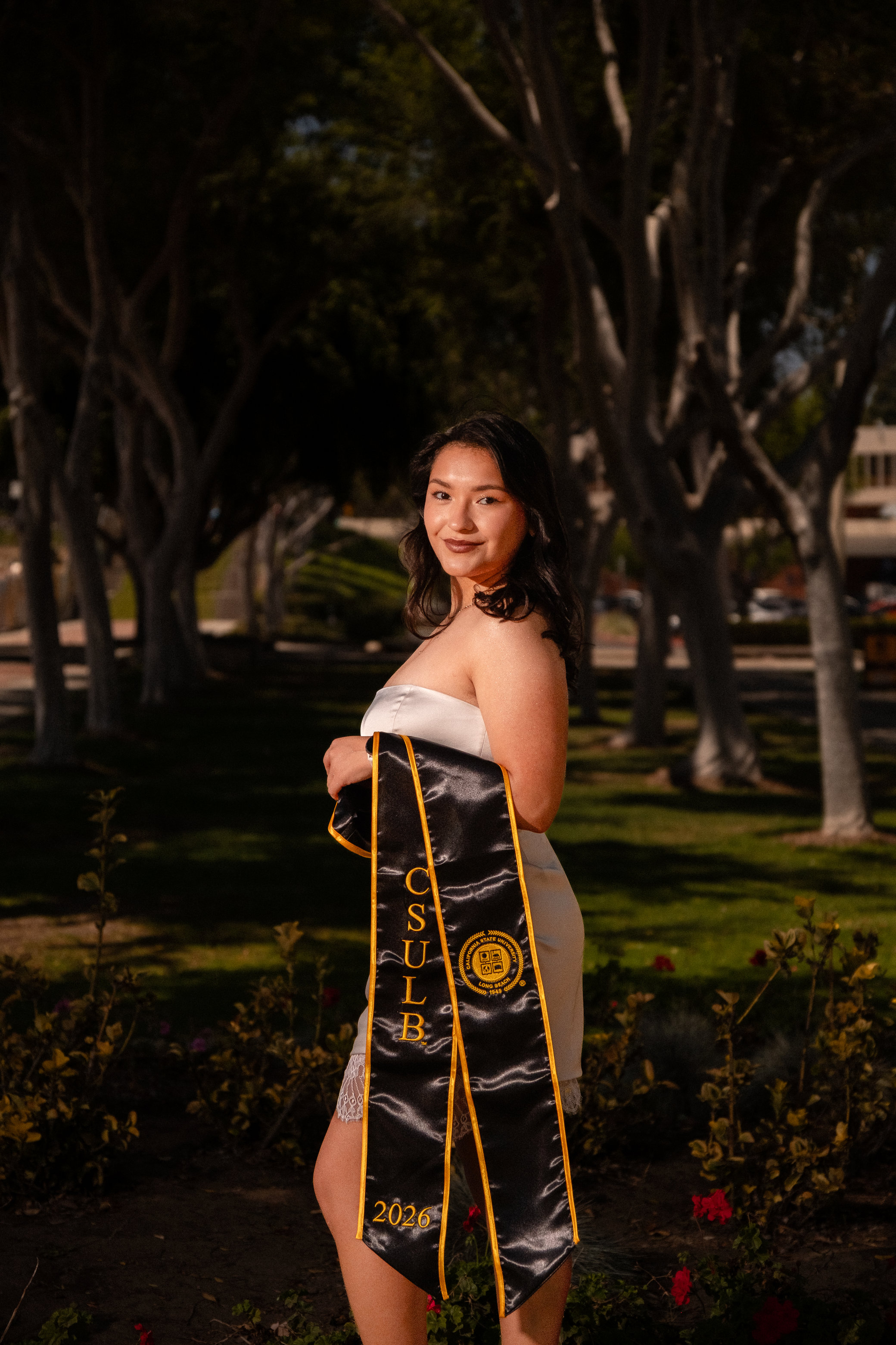 Graduate holding flowers in a sunlit park