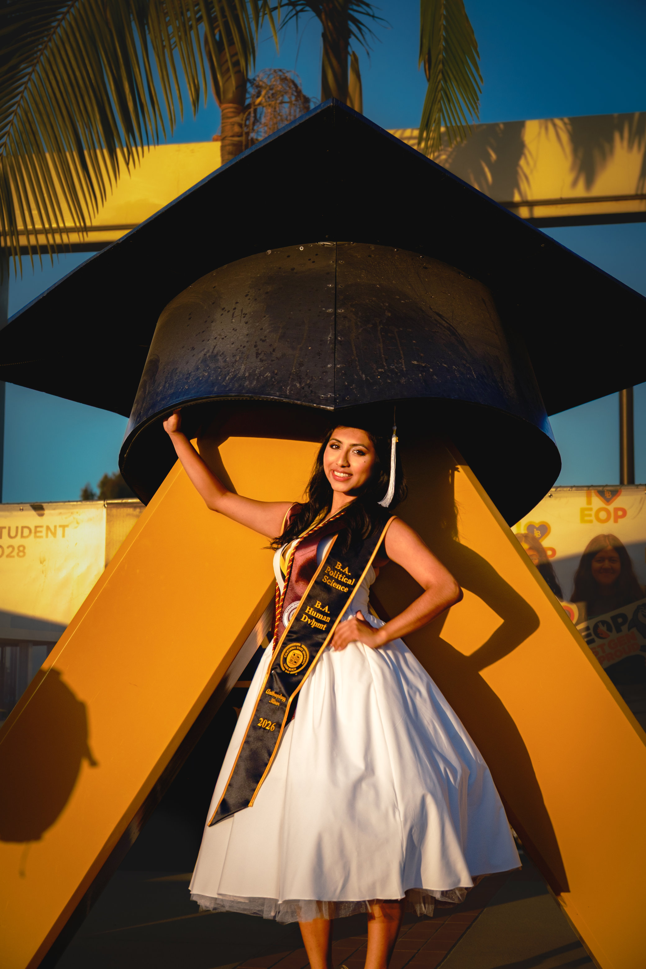 Graduate smiling in cap and gown on campus
