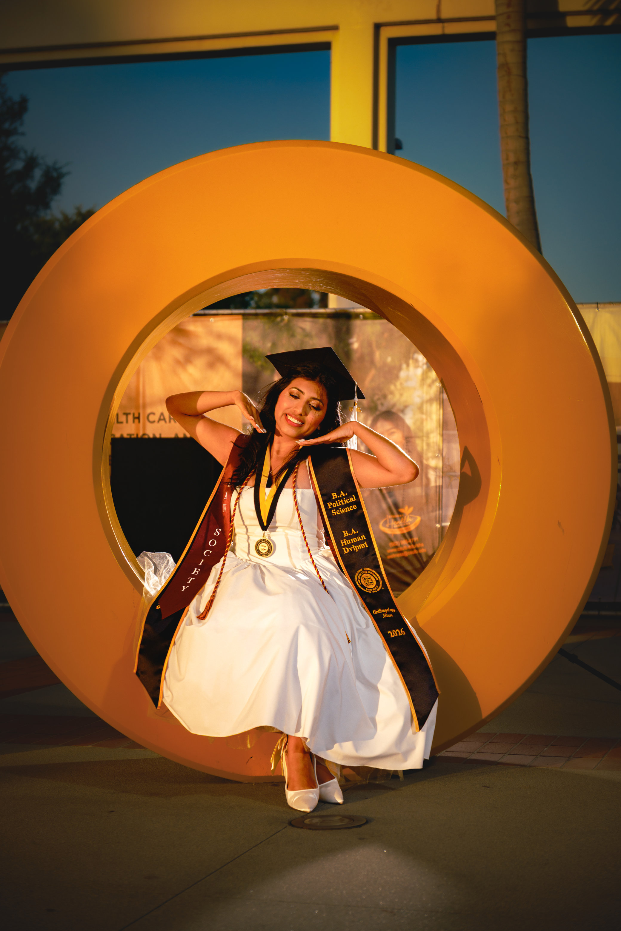 Graduate smiling in cap and gown on campus